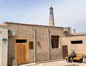 希瓦Gold Khiva的坐在有灯塔的建筑物前面的长凳上的人