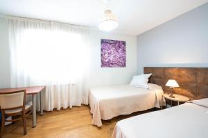 阿罗约德莱恩科缅达Apartamentos Go - Chalet Calera的客房设有两张床、一张桌子和一张书桌。