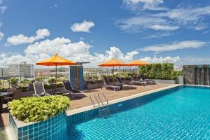 芭堤雅市中心Adelphi Pattaya - SHA Extra Plus的一座大楼内的游泳池,配有椅子和遮阳伞