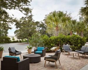 博福特博福特希尔顿花园酒店的庭院配有桌椅和棕榈树