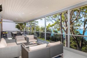 尼尔森湾Dutchie's View - Direct access to the beach的户外庭院设有柳条家具和大窗户。