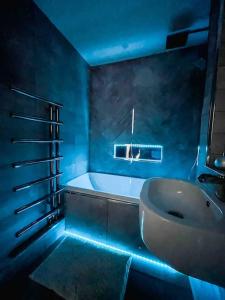 伦敦Luxury Apartment London的浴室设有水槽和蓝色灯光浴缸。