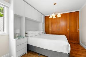 悉尼Elegant 1-Bed with Study by Balmain Wharf的卧室配有白色的床和木制橱柜。