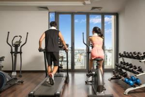 岘港Paracel Beach Hotel的一名男子和一名女子在健身房骑健身自行车