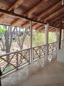 马林迪Mkuu House的阳台拥有木屋顶,后方种有树木
