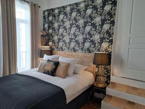 锡斯特龙Hôtel Le Patio de Sophie的一间卧室配有一张带花卉壁纸的床