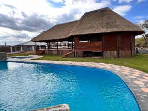 雾观Numbigate Resort & Conference的一座带茅草建筑和游泳池的度假村