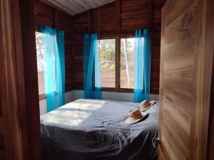 VenadoCasa Lagarto Beachfront的一间卧室配有一张带蓝色窗帘的床和一扇窗户