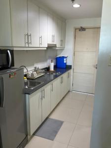 马尼拉SEA Residences in Pasay near Mall of Asia 2BR and 1BR的厨房配有白色橱柜、水槽和门