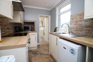AbertilleryCosy 3BR Home, Scenic Views, Ideal for Walks & Work的厨房配有白色橱柜、水槽和窗户。