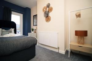 AbertilleryCosy 3BR Home, Scenic Views, Ideal for Walks & Work的一间拥有蓝色墙壁、一张床和镜子的卧室