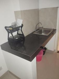 当格浪OYO 93826 Cprc Inn Serpong的厨房配有水槽和黑色台面