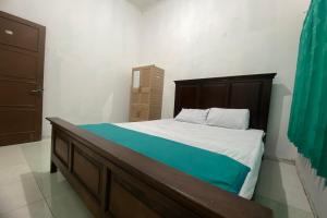 日惹OYO 93839 Aquenda Homestay的一间卧室配有一张大床和木制床头板