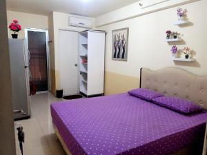 雅加达OYO 93857 Apartemen Kalibata City By Artomoro的一间卧室配有紫色床和紫色棉被