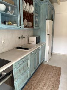 阿基奥斯·索斯蒂斯·米科诺斯Mykonian 4 Bd Ocean Dream House in Agios Sostis的厨房配有蓝色橱柜和白色冰箱