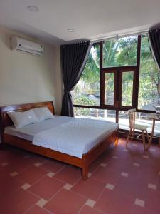 Buôn ErangKhu du lịch Suối Ong的一间卧室设有一张床和一个大窗户