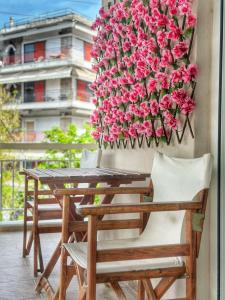 塞萨洛尼基Psimithefto Luxury Apartments的阳台配有带粉红色鲜花的桌椅