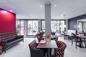 佩皮尼昂Nyx Hôtel Indépendant的一间带桌椅和红色墙壁的餐厅