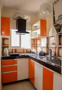 勒克瑙Bobby’s B&B的厨房配有橙色和白色的橱柜和水槽