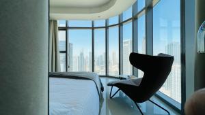迪拜Paramount Home Midtown Apartments with Infinity Sky Pool的卧室配有一张床和一张椅子,位于窗户前