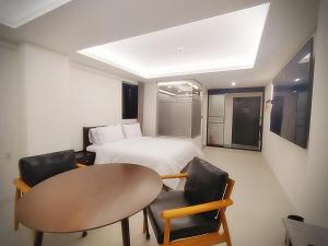 仁川市인천 연수 블루버드호텔 Bluebird Hotel的配有一张床和一张桌子及椅子的房间