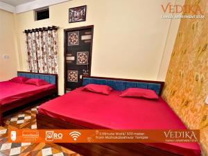 乌贾因Vedika Yatri Grah - Entire Apartment的红色床单的客房内的两张床