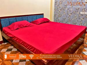 乌贾因Vedika Yatri Grah - Entire Apartment的一张大床,配有红色床单和红色枕头