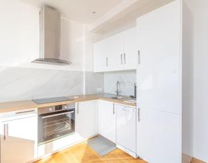 博索莱伊Amazing Sea View T2- Near Monaco的白色的厨房铺有木地板,配有白色橱柜。