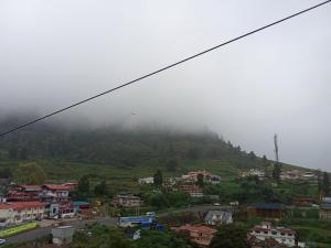 乌提Lovedale homestay的山丘上的小镇,有雾覆盖的山