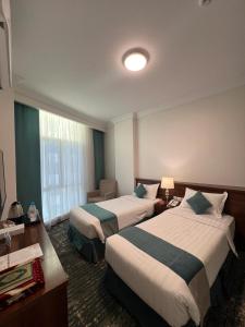 麦地那Zaha Al Madina Hotel的酒店客房设有两张床和窗户。