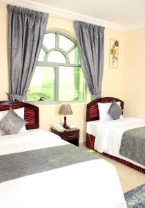 沙迦Al BARAKAH HOTEL的一间卧室设有两张床和窗户。
