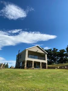 MaclearZamenkomst River Lodge的蓝天草场上的一座大建筑