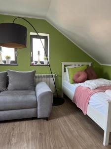 新松奇Apartament Nawojowski的一间卧室设有绿色的墙壁、一张床和一张沙发