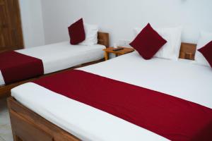 亭可马里Hotel Theevanni Inn的红色和白色的客房内的两张床