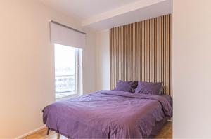 派尔努Aida 7 Apartment的一间卧室配有一张带紫色床单的床和窗户。