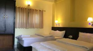 博卡拉Hotel Suite Inn Lodge的配有白色床单的酒店客房内的两张床