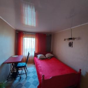 ToriTuka Talu Soomaa piirkonnas的一间设有红色床和一张桌子的小卧室