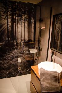 拉罗什-阿登B&B Au Canard的一间带水槽的浴室和一幅森林画
