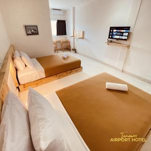 普拉亚TANAWU AIRPORT HOTEL LOMBOK的一间卧室配有两张床和一台平面电视