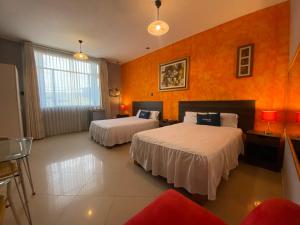 皮乌拉Suite Apart Miraflores的酒店客房带两张床和橙色墙壁
