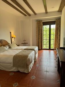 卡索拉Hotel Rural Cazorla Posada del Cordobés的一间卧室设有两张床和大窗户