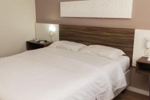 里奥格兰德Swan Rio Grande的卧室配有一张带白色床单和枕头的大床。