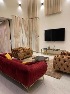库马西Luxe Vista Villa的客厅配有红色沙发和平面电视