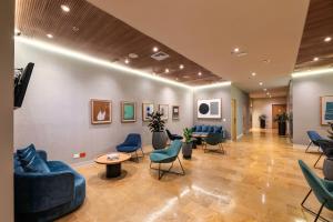 麦德林麦德林智选假日酒店及套房的一间配备有蓝色沙发和椅子的等候室