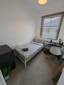 格雷夫森德2 bedroom apartment in Gravesend 10 mins walk from train station with free parking的一间卧室配有一张床、一张书桌和一个窗户。