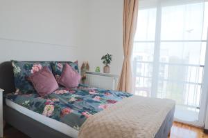 华沙Praga Premium Comfort的一间卧室配有一张带花卉图案的毯子和窗户的床。