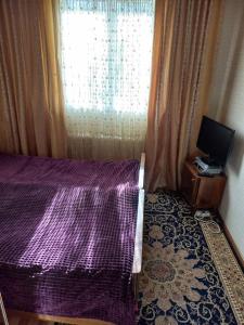 KhorogA cosy House with a wonderful Garden的一间卧室设有紫色的床和窗户