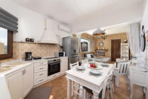 阿凡杜Evi's Afandou Suite的厨房配有白色橱柜和桌椅