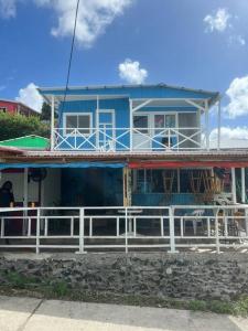 普罗维登西亚Baba’s Beach Bungalow的前面有白色围栏的蓝色房子