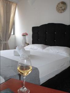 内瓦HOTEL DINASTIA REAL NEIVA的坐在床边的桌子上喝一杯葡萄酒